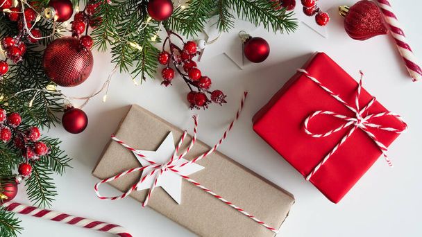 Detailní záběr vánoční novoroční dárková krabička na pozadí jedlových větví, červené koule, lízátka a věnce, výhled shora, plochá poloha, kopírovací prostor.Koncepce oslav vánočních svátků, dárky pro rodinu, přátele - Fotografie, Obrázek