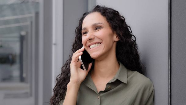 Cheerful laughing smiling happy carefree woman in city outdoors answer call talking conversation by smartphone chatting with friends boyfriend 30s lady listen joke in mobile phone good cell connection - Zdjęcie, obraz