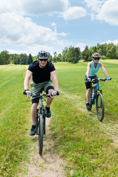 Pareja deportiva montando bicicletas de montaña en coutryside
 - Foto, Imagen