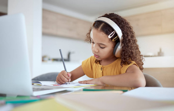 Children, education and writing with a girl student distance learning from home on a laptop for homework or study. Kids, book and school with a child at her desk to learn for growth and development. - Zdjęcie, obraz
