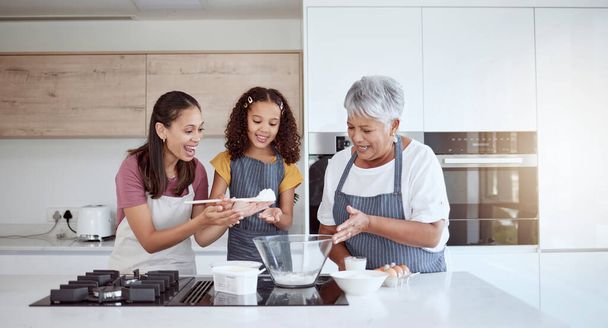 Women in kitchen teaching girl baking cake or cookies for family. Happy grandmother, mom and young child learning with cooking ingredients in family home make snack, biscuit or flour while have fun. - Photo, Image
