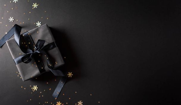 Κάτοψη των μαύρων Χριστουγεννιάτικων κουτιών δώρου με μαύρη κορδέλα σε μαύρο φόντο με χώρο αντιγραφής για κείμενο. Σύνθεση μαύρης Παρασκευής. - Φωτογραφία, εικόνα
