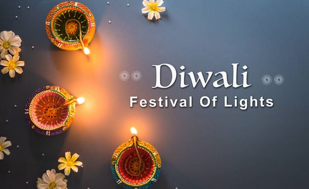 Happy Diwali - Clay Diya lamps lit during Diwali, Hindu festival of lights celebration. Colorful traditional oil lamp diya on blue background - Photo, image