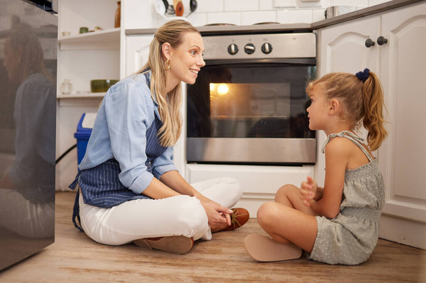 Vaření, máma a dítě v kuchyni na podlaze v domě mluvit a relaxovat při čekání na jídlo v troubě. Kanada matka těší šťastný jídlo příprava volný čas přestávka s mladou dcerou v rodinném domě - Fotografie, Obrázek