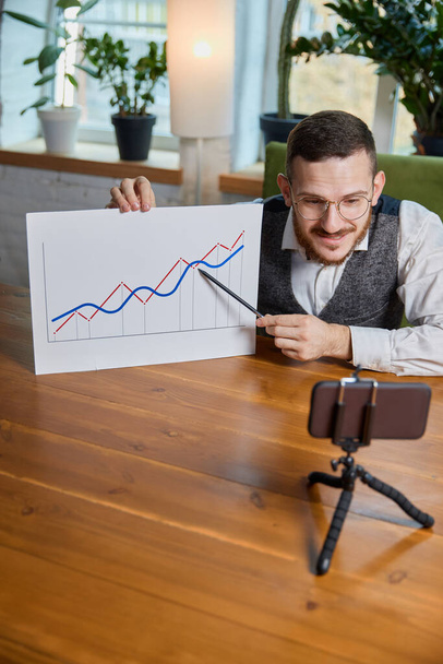 Close up male hands with pen pointing on business chart and mobile phone. People working with charts. Stock market exchange, businessman concept. Job at the desk. Online connection and communication - Valokuva, kuva