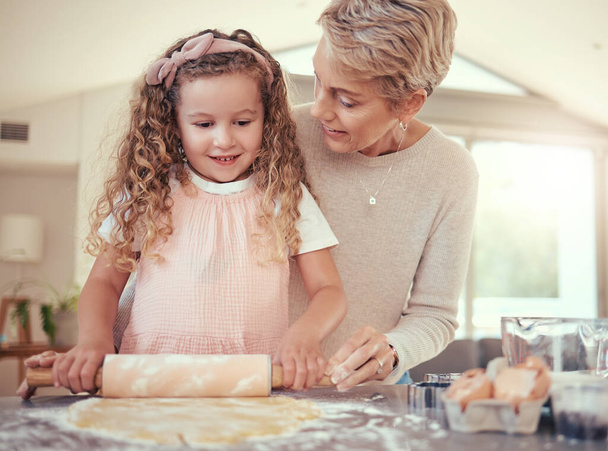 Сім'я, навчання та дівчина випікають з бабусею на кухні, зв'язуючись, готуючи печиво разом. Викладання, незалежність та розвиток дитини старшою жінкою, що показує дитині, як спекти перекус
. - Фото, зображення