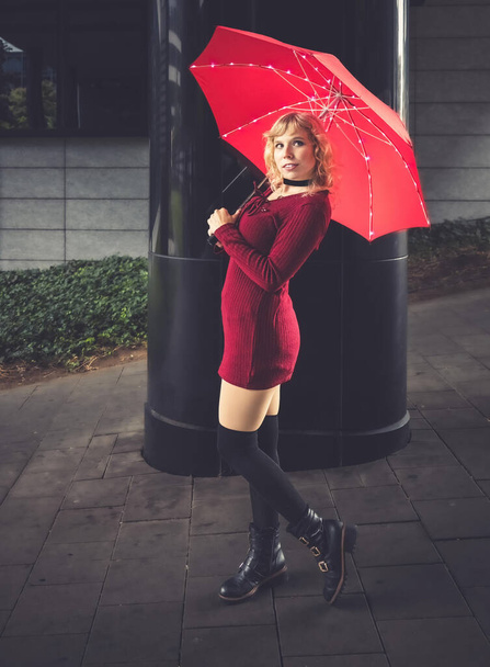 a young freindly woman with blond hair and a red umbrella - Photo, image