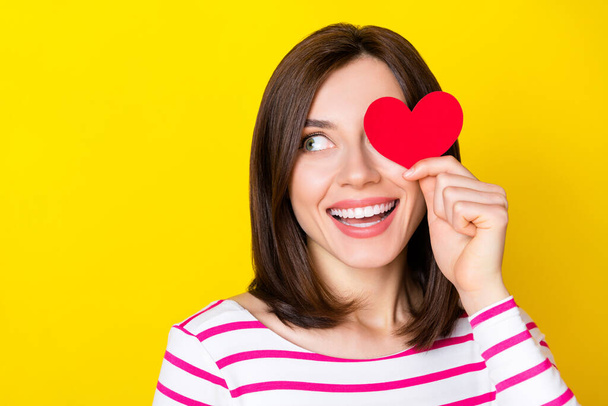 Photo of nice cute gorgeous woman with bob hairdo striped shirt look empty space hold heart close eye isolated on yellow color background. - Photo, image