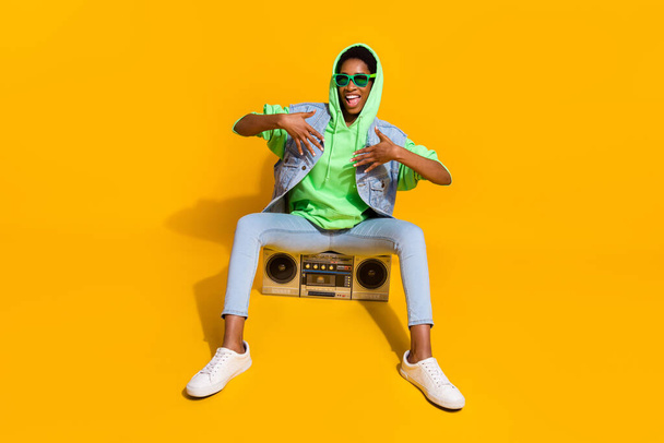 Full length photo of excited funky person sitting vintage boom box have fun isolated on yellow color background. - Foto, Bild