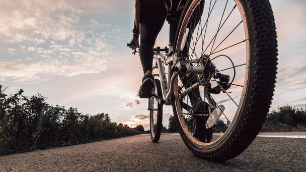 Велосипед на літньому заході сонця на плитці в міському парку. Велосипед крупним планом на розмитому літньому тлі. Велосипеди по вулиці, щоб працювати на літньому заході сонця. Концепція велосипедного та екологічного способу життя
. - Фото, зображення