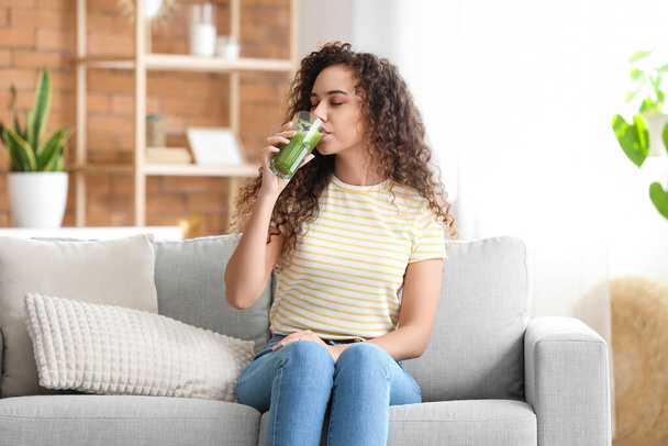 Young African-American woman drinking healthy smoothie at home - Foto, imagen