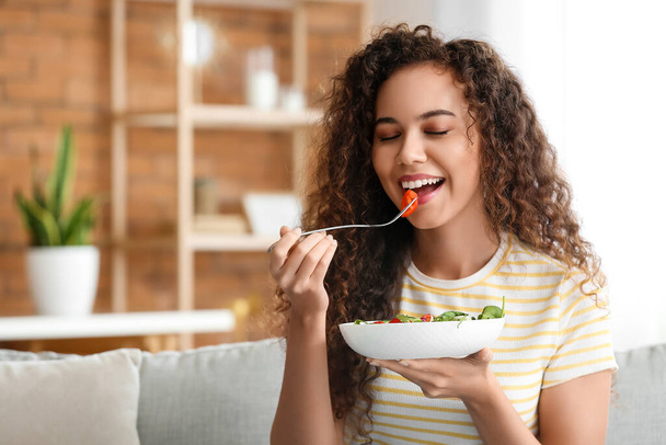Young African-American woman eating healthy salad at home. Diet concept - Photo, Image