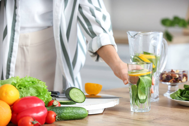 Young woman drinking infused water in kitchen, closeup - Photo, Image