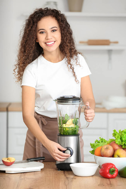 Young African-American woman making healthy smoothie in kitchen - Photo, Image