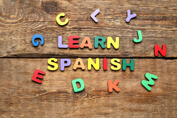 Text LEARN SPANISH and letters on wooden background - Fotoğraf, Görsel