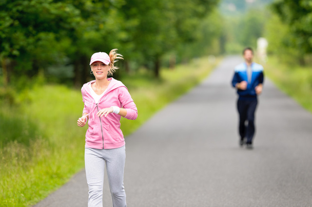 Jogging sportive young couple running park road - Фото, изображение