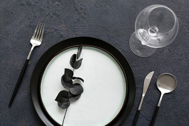 Stylish table setting with eucalyptus branch on dark background, closeup - Foto, afbeelding