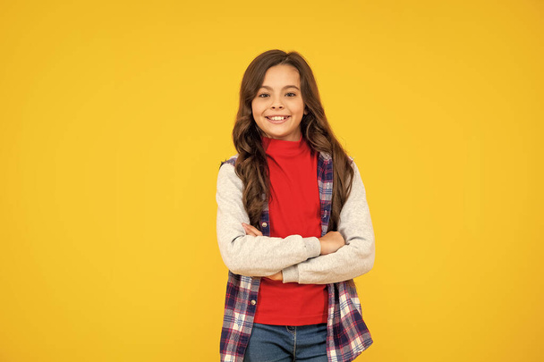 smiling kid in casual clothes on yellow background. happy childhood. child express positive emotions. teen girl has long curly hair. back to school. female fashion model. - Φωτογραφία, εικόνα