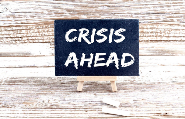 CRISIS AHEAD text on Miniature chalkboard on wooden background - Photo, Image