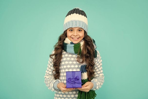 happy child in knitwear hold box. kid with present. teen girl on blue background. winter holidays. - 写真・画像