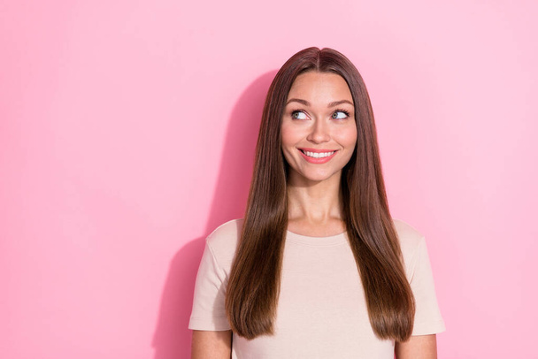 Photo of adorable cheerful girl beaming smile look interested empty space isolated on pink color background. - Foto, Imagem
