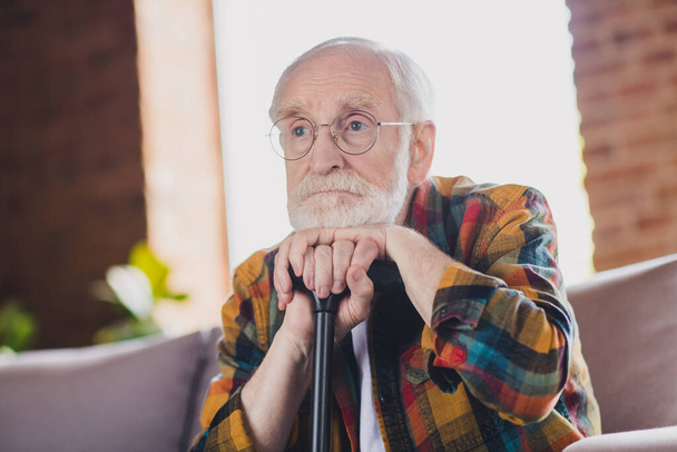Photo of upset depressed grandpa grey hair head lean walking stick wear casual checkered look eyewear sitting cozy sofa indoors home room. - Fotó, kép