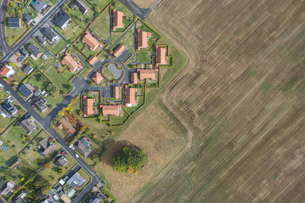 Aerial view on private houses situated close to a field. People and nature. Little European village. Modern village and a big field. Contrasts.  - Foto, immagini