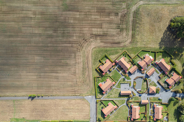 Vue aérienne sur des maisons privées situées à proximité d'un champ. Les gens et la nature. Petit village européen. Village moderne et un grand champ. Contrastes.  - Photo, image