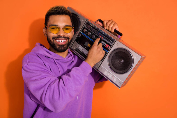 Portrait of cheerful excited guy carry boombox turn on song have good mood isolated on orange color background. - Φωτογραφία, εικόνα