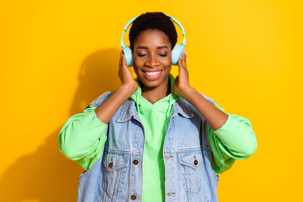 Portrait of attractive dreamy cheerful girl listening hit single bass isolated over bright yellow color background. - Foto, Imagem
