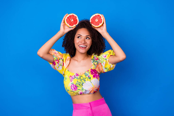 Portrait of attractive cheerful lady arms hold half grapefruit look empty space isolated on blue color background. - Zdjęcie, obraz
