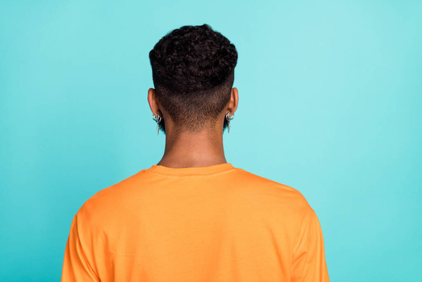 Photo of attractive handsome man dressed orange t-shirt standing back showing new haircut isolated turquoise color background. - Фото, изображение