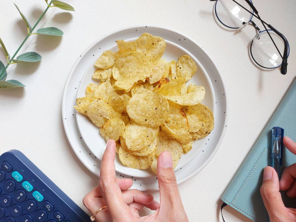 Kartoffelchips oder Chips. Es ist eine dünne Scheibe Kartoffel, die frittiert, gebacken oder frittiert bis sie knusprig ist. Sie werden häufig als Vorspeise, Beilage oder Vorspeise serviert. Serviert auf weißem Teller - Foto, Bild