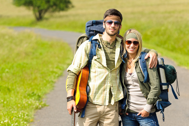 Hiking young couple backpack tramping asphalt road - 写真・画像