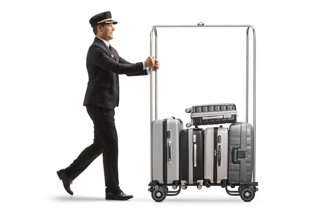 Bellboy pushing suitcases on a hotel luggage cart isolated on white background - Photo, image