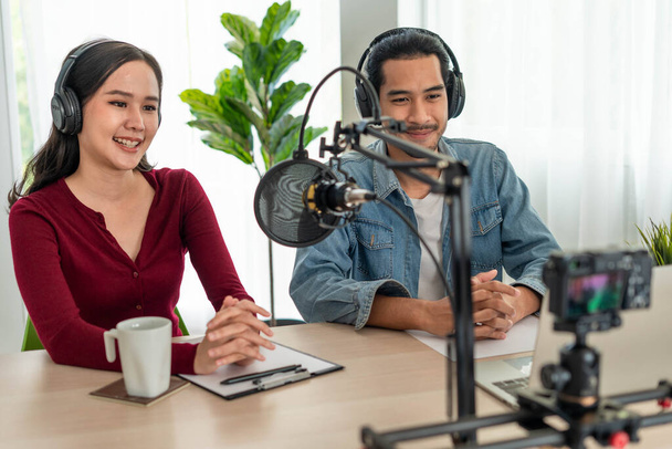 Asian Radio Host Podcast Чоловічий і жіночий динаміки спілкуються через мікрофони і камери на своїх комп'ютерах. Живіть зранку. - Фото, зображення