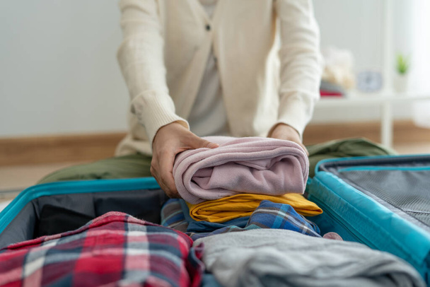 Utazó táskák nyaraláshoz. Egy fiatal nő ruhákat és személyes tárgyakat készít a bőröndjébe. Csomagolj össze utazás előtt. - Fotó, kép