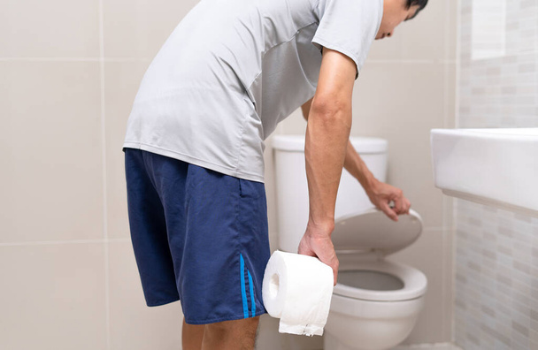 Man standing in bathroom holding tissues with severe stomach pain. stomach cramps, Abdominal pain, Diarrhea, Colon or belly cancer  - Foto, imagen