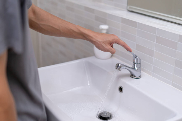 The faucet in the bathroom with running water. Man keeps turn off the water to save water energy and protect the environment. save water concept - Foto, Imagem