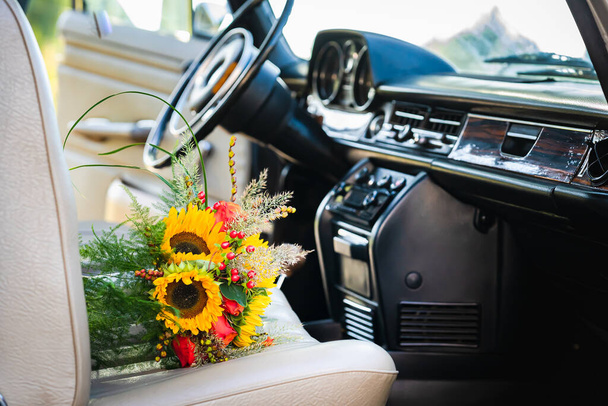 Oldtimer Hochzeitsauto mit reizendem Brautstrauß voller Rosen und Sonnenblumen - Foto, Bild