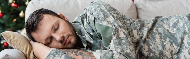 unshaven man in camouflage sleeping on sofa at home, banner - Photo, Image
