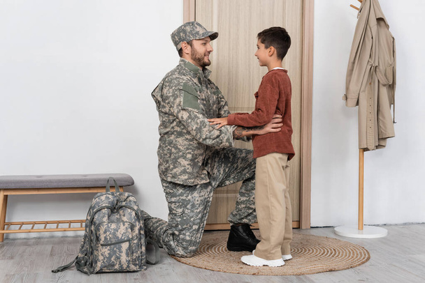 father in camouflage looking at happy son meeting him at home - Photo, Image