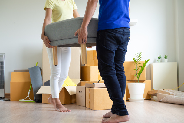 Emménager dans une nouvelle maison et déménager. Le mari et la femme déplacent le canapé et arrangent les meubles. concept résidentiel et immobilier - Photo, image