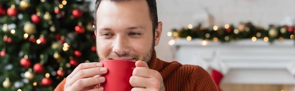 elégedett férfi iszik meleg kakaó karácsonykor otthon, banner - Fotó, kép