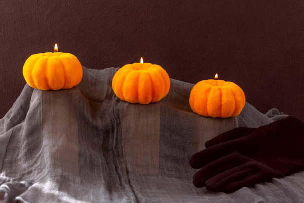 Halloween. Yellow pumpkins lie on stands on a gray cloth. Lights are burning above them. There is a black glove next to it. Tinting - Photo, Image