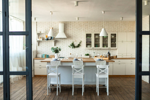 Moderni sisustus, sisustuskonsepti. Nykyaikainen keittiö ja ruokasali sisustus pöytä, tuolit, mukavat huonekalut ja puulattia. Trendikäs minimalismi, skandinaavinen tyyli - Valokuva, kuva
