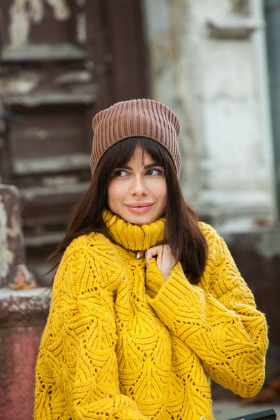 Linda morena européia vestida com um suéter de lã amarela e chapéu fora. A menina bonita que usa roupas grossas e elegantes de outono em tempo fresco. - Foto, Imagem