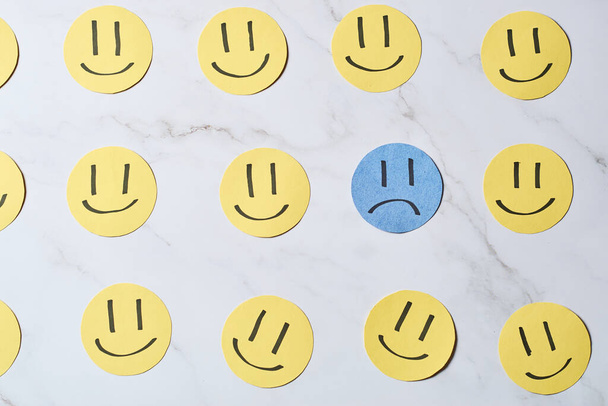 Sad face surrounded by happy faces. Depression and sadness disorder concept. - Valokuva, kuva