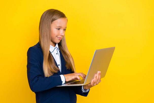 Photo of smart clever positive girl hold use netbook chatting texting classmates friends empty space isolated on yellow color background. - Foto, imagen