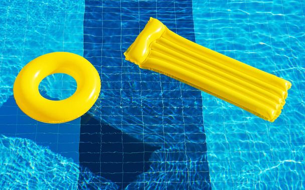 anello galleggiante e materasso sull'acqua blu della piscina - Foto, immagini